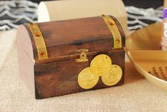 a wooden box sitting on top of a table next to a gold plate and bowl