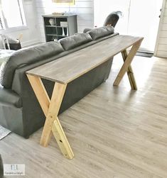 a wooden table sitting on top of a hard wood floor next to a gray couch