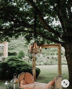 a bed sitting under a tree next to a lush green field