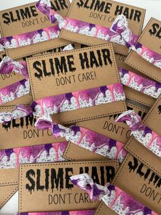 some pink and purple hair ties on top of brown tags with words saying slime hair don't care