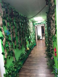 a long hallway with green walls and plants growing on the wall, along with wooden flooring