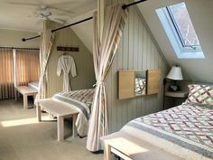 a bed room with two beds and a ceiling fan in it's corner next to a window