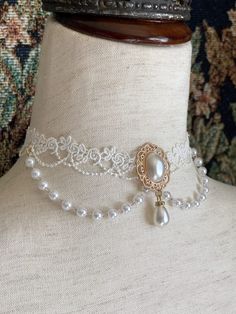 This beautiful Rococo & Regency inspired choker necklace is dripping in faux pearls, and white floral lace; making it the perfect historical accessory to tie-together an outfit for a ball or promenade! Sizing: One SizeNeck Circumference 12-16 Inches / 30.5-40.5 CentimetersAdjustable claw clasp 1905 Dresses, Rococo Inspired Outfits, Pearl Choker Necklace Design, Rococo Necklace, Victorian Jewellery Designs, 1905 Dress, Rococo Outfit, Rococo Accessories, Floral Necklaces