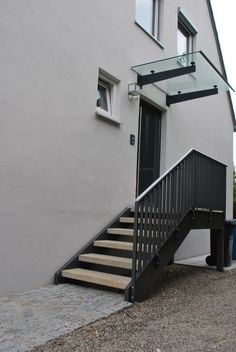 the stairs lead up to the front door of an apartment building with glass railings