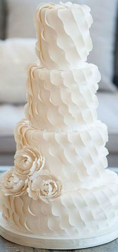 a three tiered white wedding cake sitting on top of a table next to a couch