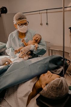 a woman in a hospital gown holding a baby while wearing a mask and goggles