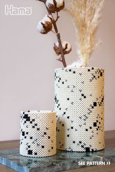 two vases sitting on top of a table with dried flowers in the middle and one is made out of knitted material