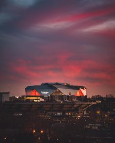 the stadium is lit up at night with red clouds