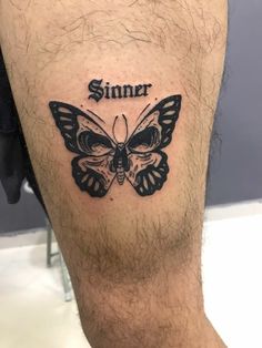 a man's leg with a butterfly tattoo on it that says, sinner