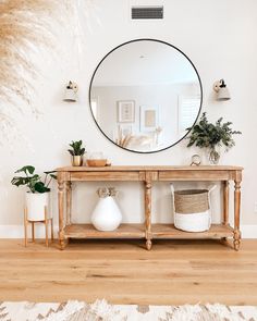 a mirror on the wall above a wooden table with potted plants in front of it