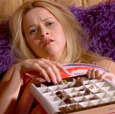 a woman laying in bed with a chocolate box