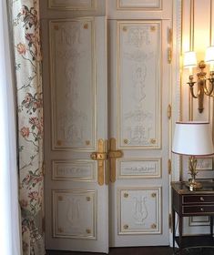 an ornately decorated room with two doors and a lamp on the table in front of it