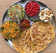 a metal plate topped with different types of food next to bowls of salad and nuts