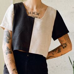 a woman with tattoos standing next to a plant