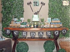 a table topped with a cake covered in green frosting and surrounded by greenery