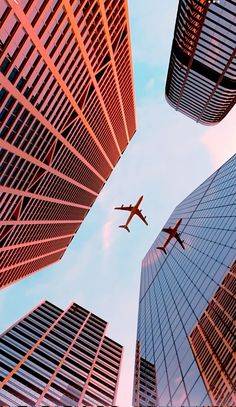 an airplane flying through the sky between two tall buildings