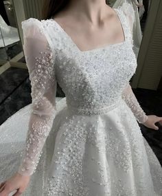 a woman wearing a wedding dress with long sleeves and beading on the bouncy