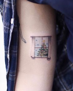 a small christmas tree tattoo on the arm