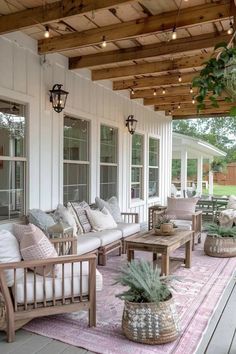 a covered porch with couches, tables and potted plants on the rugs