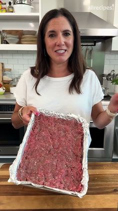 a woman holding up a large piece of meat