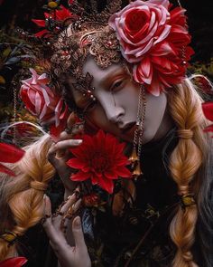 a woman with red flowers in her hair and make - up on her face is surrounded by feathers