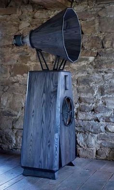 an old fashioned wooden speaker on display in a stone walled room with wood flooring