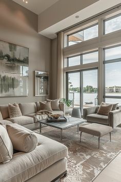 a living room filled with lots of furniture and large windows overlooking the water in front of it