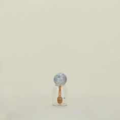 a small glass jar with a wooden spoon in it and a marble ball on top