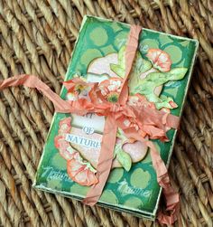 a green box with flowers on it sitting on a wicker tableclothed surface