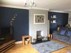 a living room with blue and gray walls, wood flooring and a grey couch