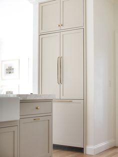 a kitchen with white cabinets and wood floors