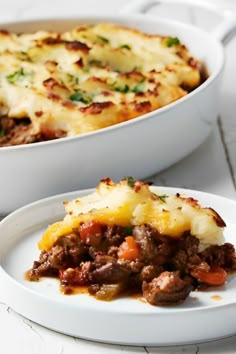 a white plate topped with a casserole covered in meat and cheese next to another dish