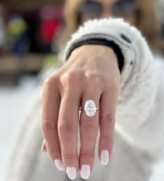 a woman's hand with a diamond ring on her finger, in the snow