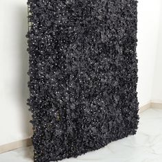 a black square sculpture sitting on top of a marble floor next to a white wall