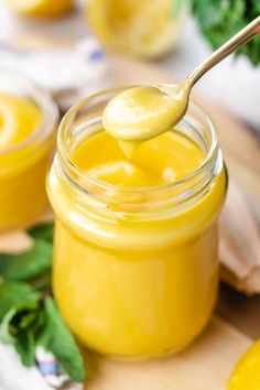 a spoon full of lemon curd sitting on top of a wooden cutting board