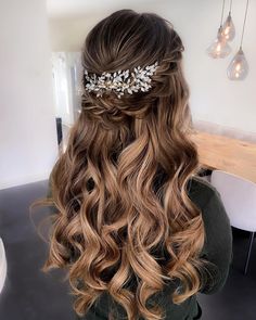 the back of a woman's head with long wavy hair and flowers in her hair