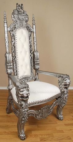 an ornate silver chair with white upholstered seat and arm rests on wood flooring