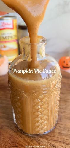 a bottle filled with liquid sitting on top of a wooden table next to pumpkins