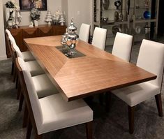 a dining room table with white chairs and a wooden centerpiece on top of it