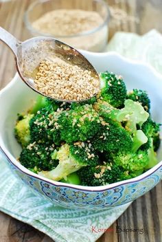 broccoli with sesame seeds in a blue and white bowl on a wooden table