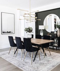 a dining room table with black chairs and a mirror on the wall in front of it