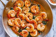 shrimp and spinach stir fry in a pan on a marble countertop next to a bowl of seasoning