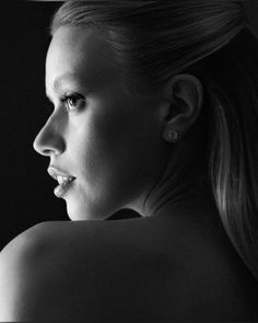 a black and white photo of a woman's face with her hair pulled back