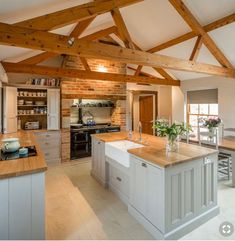 a large kitchen with an island in the middle and wooden beams on the ceiling above it