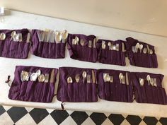 there are forks, spoons and knives in the purple pouches on the table