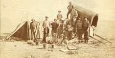 a group of men standing next to each other in front of a tent on top of a field