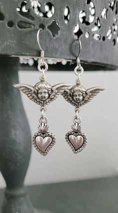 Adorn yourself with these  beautiful antique silver metalwork sweet cherub angels and milagros hearts  * Both sides are the same. * Lightweight.  These earrings are  2.0" inches long.  All jewelry materials are resourced from The United States, Italy , Portugal, Spain and The United Kingdom.  All jewelry is free of lead, free of nickel and eco-friendly. Light weight earrings.  All my jewelry is made and designed with love for you to express yourself and your life with happiness, beauty and spiri Victorian Jewelry Earrings, Silver Victorian Jewelry, Sacred Heart Earrings, Cherub Earrings, Alt Accessories, Jewelry Materials, Angel Earrings, Angel Heart, Earrings Antique