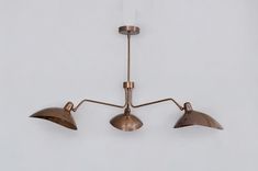 three lights are hanging from the ceiling in an industrial style setting, one is brass and the other is copper