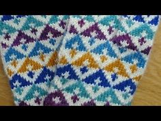 two colorful crocheted ties sitting on top of a wooden table next to each other