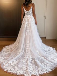 a woman in a white wedding dress standing on a wooden floor with her back to the camera